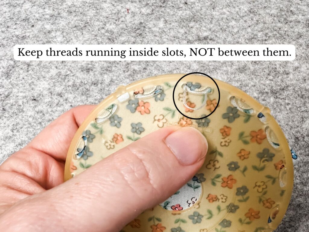 Clover Yo-Yo Maker with Playtime 30's print square of fabric. Keep the threads running inside slots, NOT between them.