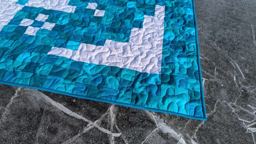 Early Bloomer pixel quilt made with solid turquoise fabrics and the Lights On II collection of white-on-white fabrics by Riley Blake Designs